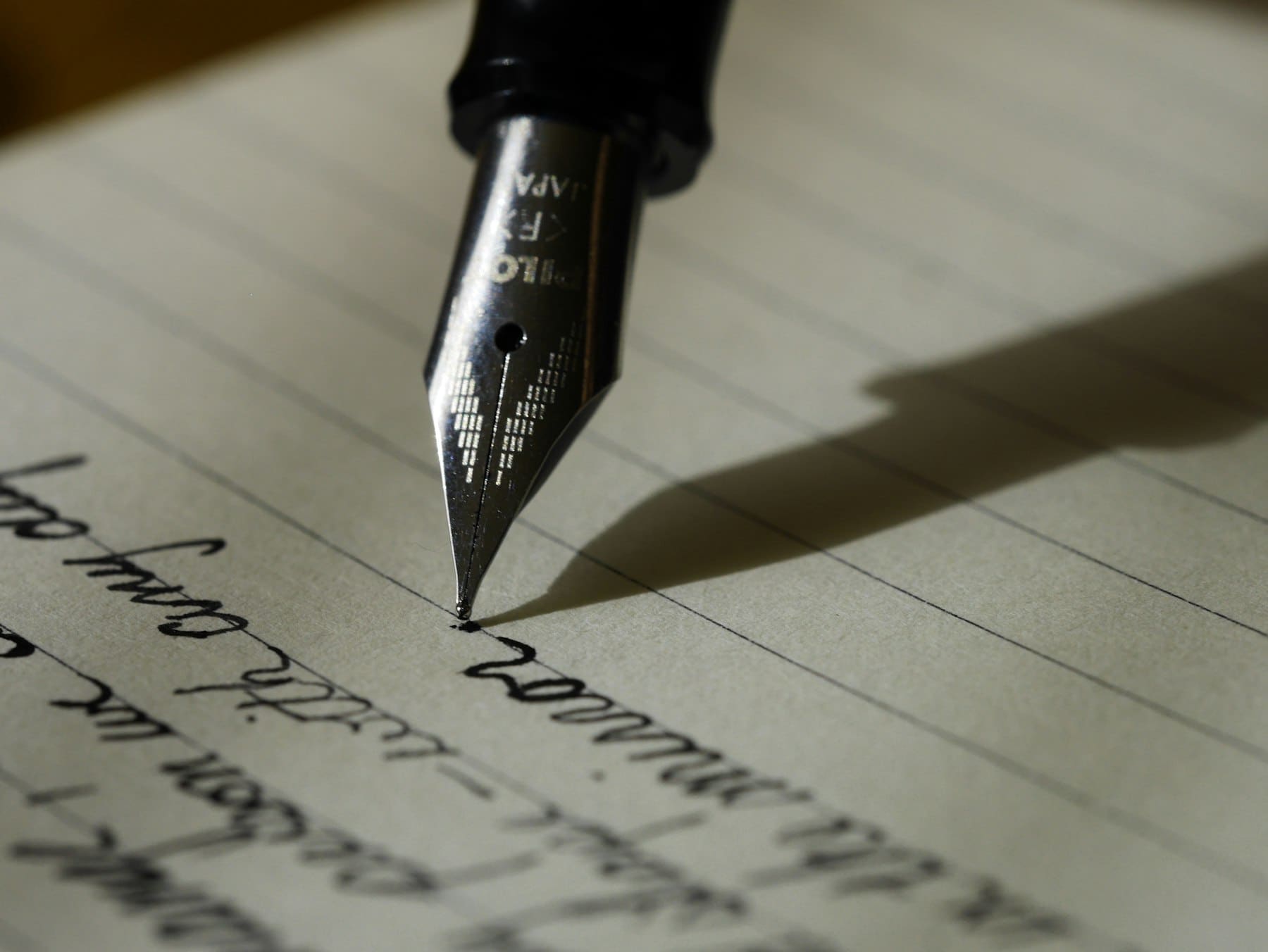 A fountain pen writing on cream paper